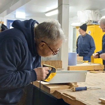 Member of Lybster Mens Shed sawing wood.